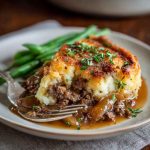Amish hamburger steak bake casserole with melted cheese and golden potatoes