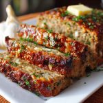 Mouthwatering garlic parmesan meatloaf baked golden brown, topped with melted cheese and fresh herbs, sliced and served on a rustic platter.