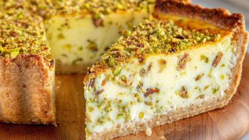 Slice of baked pistachio custard pie topped with whipped cream and crushed pistachios