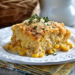 Slow cooker cream cheese corn casserole with golden, creamy corn filling served in a rustic dish, garnished with fresh herbs.