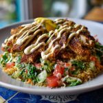 Chicken shawarma crispy rice salad topped with spiced chicken, fresh vegetables, crispy rice, and drizzled with lemon-tahini dressing.