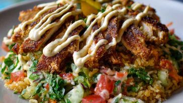 Chicken shawarma crispy rice salad topped with spiced chicken, fresh vegetables, crispy rice, and drizzled with lemon-tahini dressing.