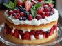 Heavenly berry trifle cake layered with fluffy sponge, creamy custard, fresh berries, and whipped cream in a glass dish.