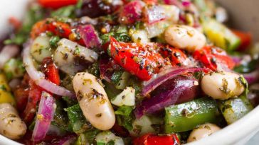 Colorful marinated za’atar bean salad with chickpeas, white beans, fresh herbs, and za’atar dressing served in a rustic bowl.