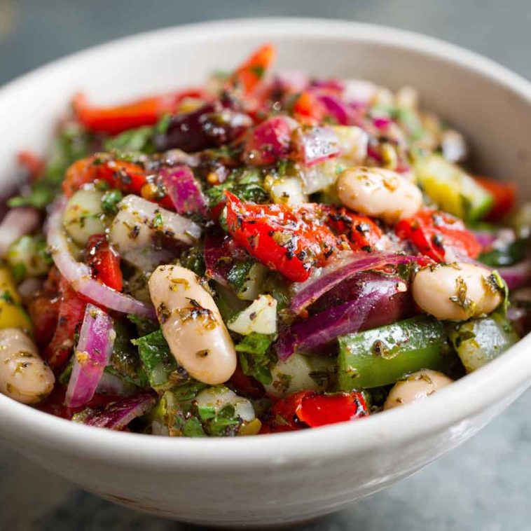 Colorful marinated za’atar bean salad with chickpeas, white beans, fresh herbs, and za’atar dressing served in a rustic bowl.