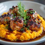 "A plate of juicy pork meatballs served over creamy sweet potato mash, drizzled with bourbon-maple sauce."