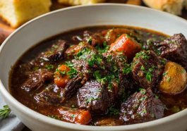 Rustic French-style beef stew simmered in red wine with carrots, onions, and herbs served in a cast-iron pot.