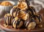 No-bake peanut butter cheesecake balls coated in chocolate and drizzled with peanut butter, served on a dessert tray.