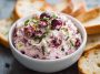 Bowl of cranberry jalapeño cream cheese dip garnished with fresh herbs