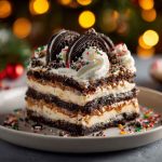 Layered no-bake Oreo Christmas lasagna topped with whipped cream and festive sprinkles.