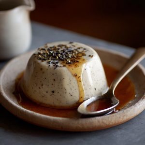 "A glass of creamy Earl Grey panna cotta topped with whipped cream and garnished with fresh berries."