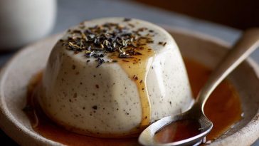 "A glass of creamy Earl Grey panna cotta topped with whipped cream and garnished with fresh berries."