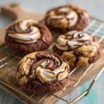 Chocolate marshmallow swirl cookies with gooey marshmallow ribbons baked into rich chocolate cookie dough, served on a rustic tray.