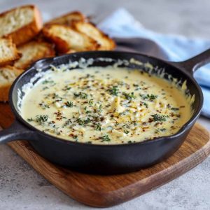Creamy Mornay sauce poured over vegetables and pasta, garnished with fresh herbs in a rustic serving dish.