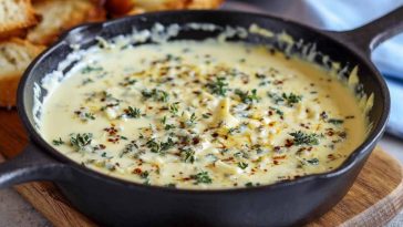 Creamy Mornay sauce poured over vegetables and pasta, garnished with fresh herbs in a rustic serving dish.