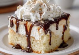 White Russian poke cake infused with coffee liqueur and vodka, topped with creamy whipped frosting and chocolate drizzle.
