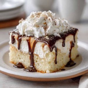 White Russian poke cake infused with coffee liqueur and vodka, topped with creamy whipped frosting and chocolate drizzle.