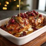 Golden baked chicken topped with honey cranberry glaze and creamy ricotta cheese, served in a casserole dish.