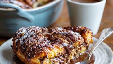 Chocolate croissant breakfast bake made with flaky croissants layered with rich chocolate and custard, baked golden brown in a casserole dish.