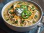 Creamy white cheddar apple chicken chili served in a rustic bowl, topped with shredded cheese and fresh herbs.