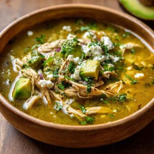 Bowl of creamy chicken poblano soup with tender chicken, roasted poblano peppers, corn, and fresh cilantro garnish.