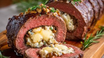 Quick Christmas stuffed beef tenderloin filled with savory herbs, garlic, and cheese, sliced and served on a festive holiday platter.