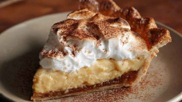 “A golden-brown cinnamon-vanilla custard pie topped with a dusting of cinnamon and served on a festive table.”