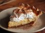 “A golden-brown cinnamon-vanilla custard pie topped with a dusting of cinnamon and served on a festive table.”
