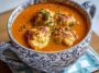 Bowl of homemade tomato soup topped with fluffy cheddar bay dumplings and fresh herbs.