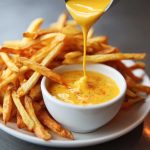 "Golden crispy fries drizzled with rich, creamy ultimate cheese sauce, garnished with fresh herbs."