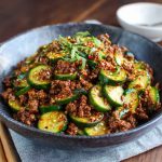 Spicy Korean ground beef served with fresh cucumber salad, garnished with sesame seeds and scallions.
