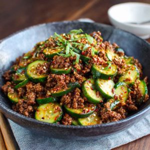 Spicy Korean ground beef served with fresh cucumber salad, garnished with sesame seeds and scallions.