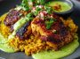 "Peruvian chicken and rice served with vibrant green sauce, garnished with fresh cilantro and lime wedges."