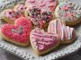 Homemade Valentines cookies decorated with pink and red icing, heart-shaped sprinkles, and festive designs arranged on a platter.