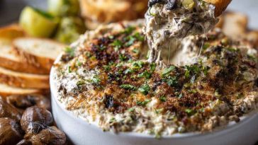 “Golden, cheesy stuffed mushroom dip served in a skillet, topped with herbs and bubbling Parmesan.”
