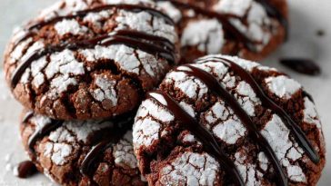 Stack of chocolate crinkle cookies dusted with powdered sugar on a festive plate.