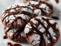 Stack of chocolate crinkle cookies dusted with powdered sugar on a festive plate.