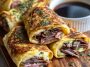 “Golden baked French dip tortilla roll ups filled with roast beef, melted cheese, and served with au jus dipping sauce.”