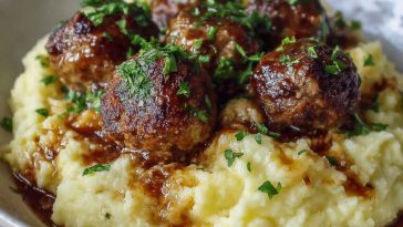 Salisbury steak meatballs served over garlic herb mashed potatoes with rich brown gravy.