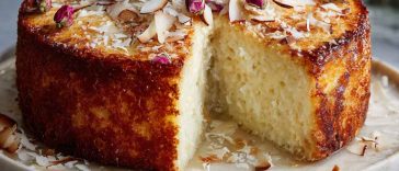 "Fluffy coconut ricotta cream cake topped with shredded coconut and dusted with powdered sugar, served on a cake stand."