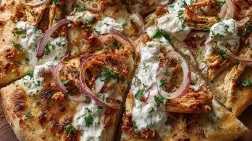 Cajun shrimp and chicken pizza drizzled with creamy tzatziki sauce and garnished with fresh herbs.