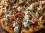Cajun shrimp and chicken pizza drizzled with creamy tzatziki sauce and garnished with fresh herbs.