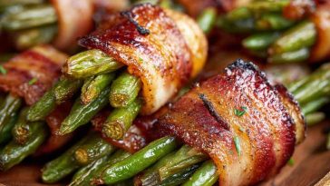 "Crispy bacon-wrapped green bean bundles baked to perfection, garnished with fresh herbs on a serving platter."