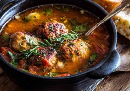 “A hearty bowl of Italian meatball soup with tender meatballs, pasta, vegetables, and fresh herbs served with bread.”