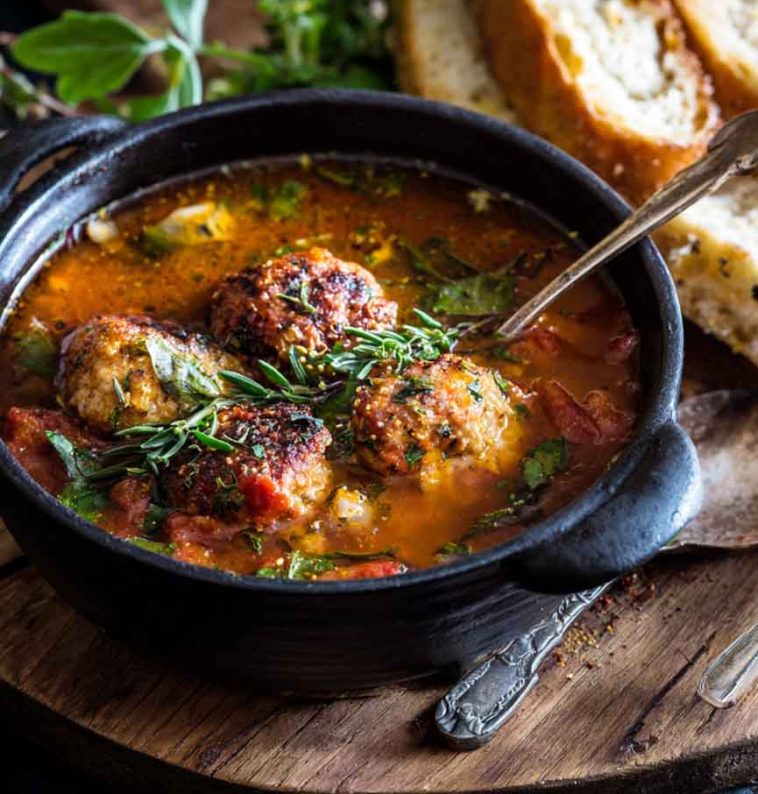 “A hearty bowl of Italian meatball soup with tender meatballs, pasta, vegetables, and fresh herbs served with bread.”