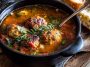 “A hearty bowl of Italian meatball soup with tender meatballs, pasta, vegetables, and fresh herbs served with bread.”
