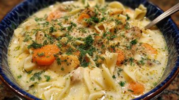 “A steaming bowl of Amish snow day soup filled with noodles, vegetables, and tender chicken, served with rustic bread.”