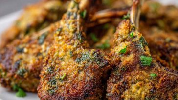 "Golden garlic parmesan fried lamb chops served on a platter, garnished with fresh herbs and grated parmesan."