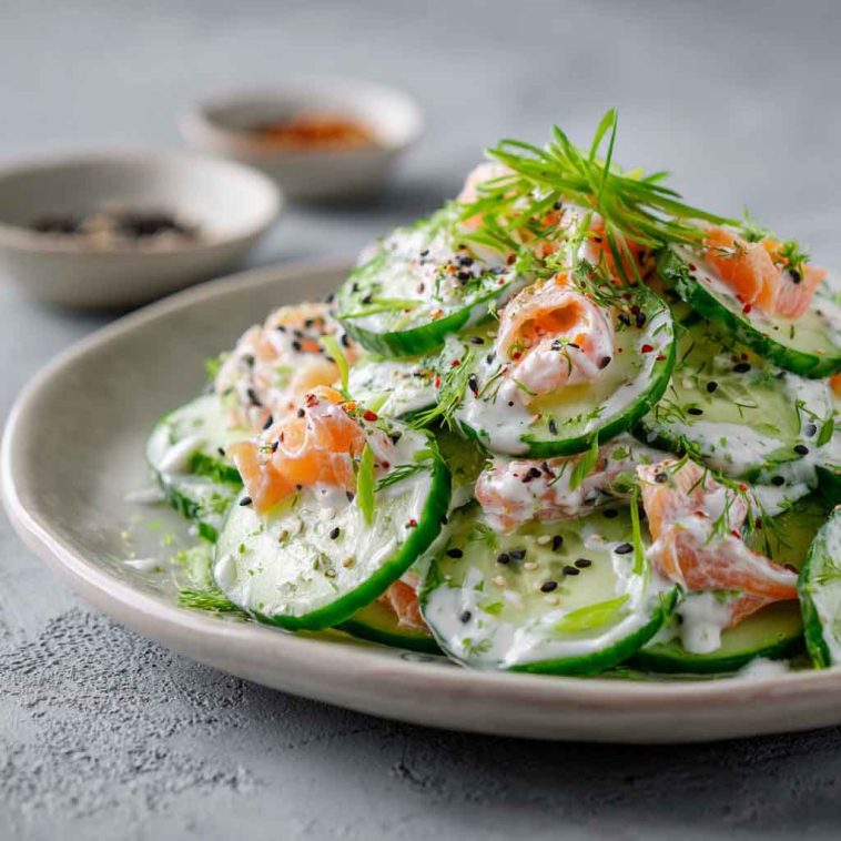 Creamy cucumber salad with sesame seeds and herbs served in a bowl.