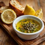 "A small dish of simple lemon caper sauce with fresh lemon slices and capers, served alongside grilled fish."